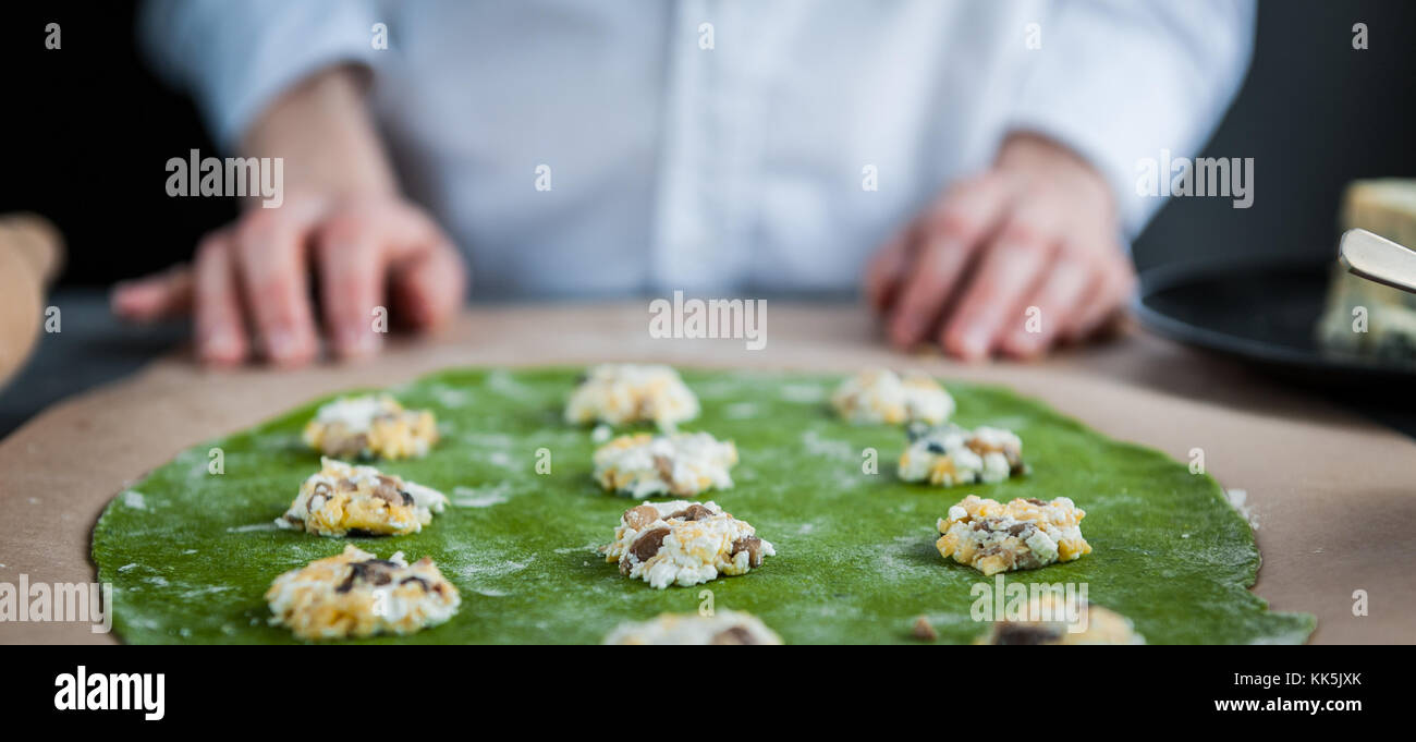 La pâte pour rouleaux chef ravioles aux épinards ajouter à la pâte, farcie aux cèpes et ricotta. avec des oeufs de caille poché. sur une sombre retour Banque D'Images