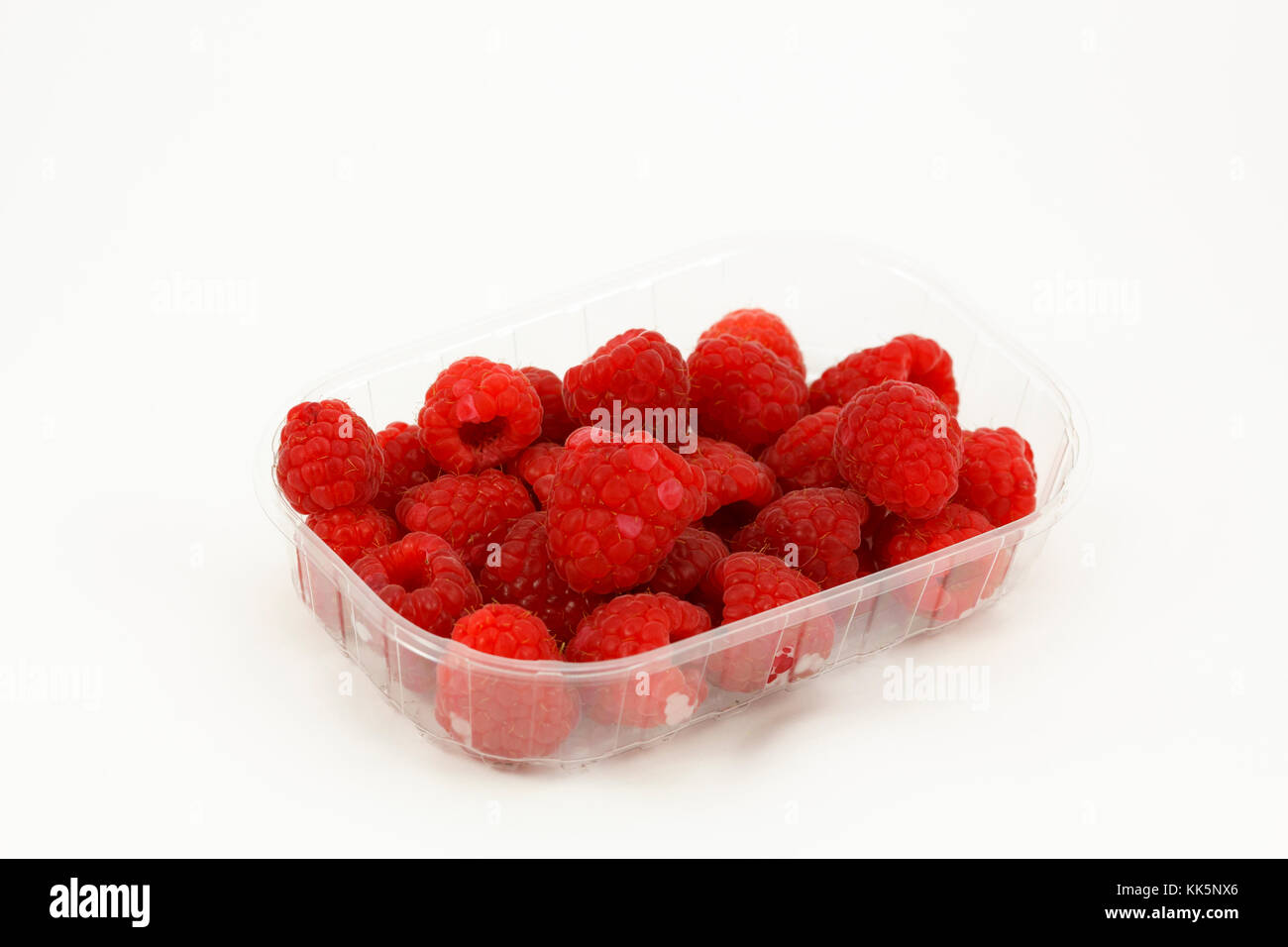 Framboises dans une boîte en plastique, isolé dans un fond blanc Banque D'Images