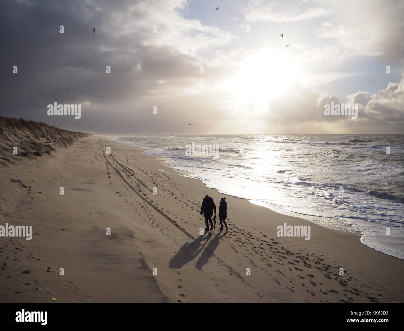 Deux personnes de retour à marcher le long de la plage de Sylt en fin d'après-midi Banque D'Images