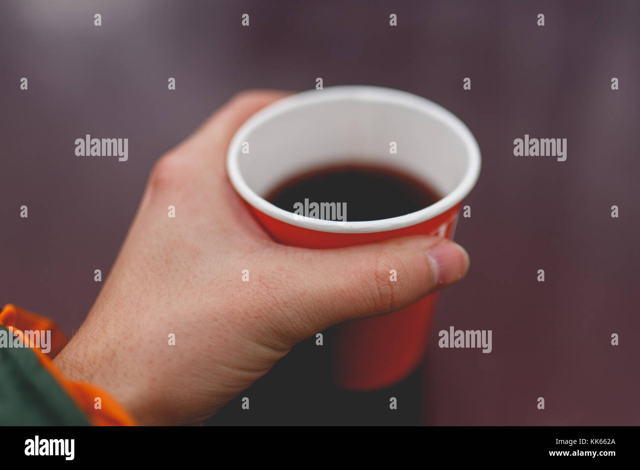 Photo de man's hand holding papier rouge avec plateau en verre sur fond violet floue Banque D'Images