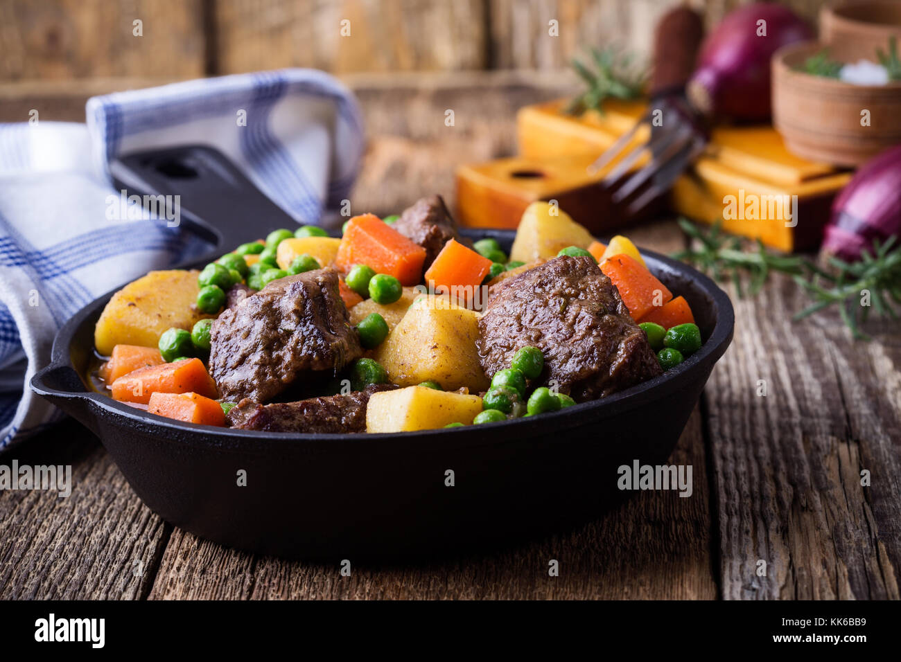 Ragoût de légumes et de boeuf avec des pommes de terre dans la poêle en fonte sur rural tableau Banque D'Images