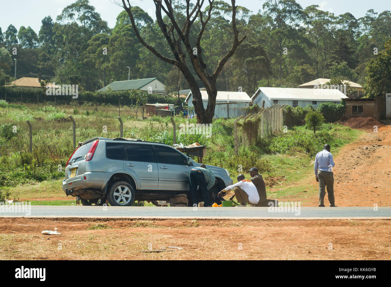 Un groupe d'hommes africains pneu crevé de fixation sur le côté de la route, Kenya, Afrique de l'Est Banque D'Images