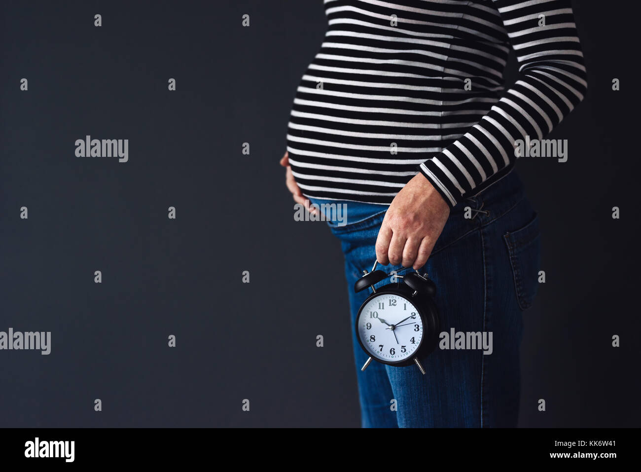 Les femmes enceintes avec vintage réveil attend bébé dans le troisième trimestre de la grossesse Banque D'Images