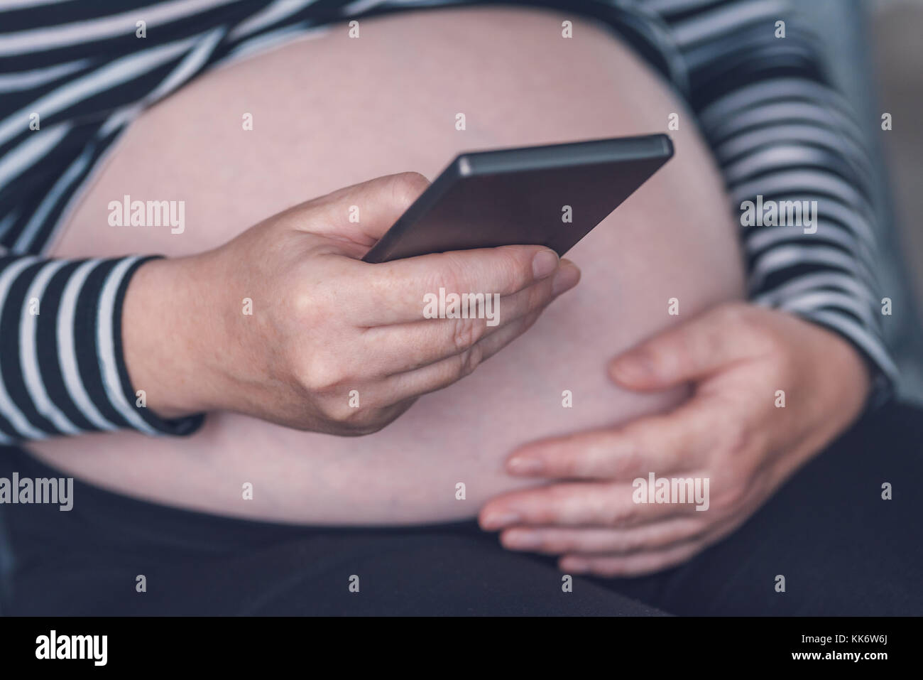 Femme enceinte en utilisant son smartphone pendant la grossesse Banque D'Images