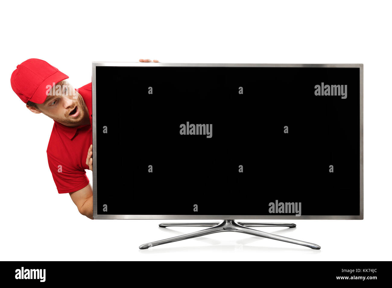 Surpris jeune homme en uniforme rouge à la recherche de big blank écran de télévision Banque D'Images