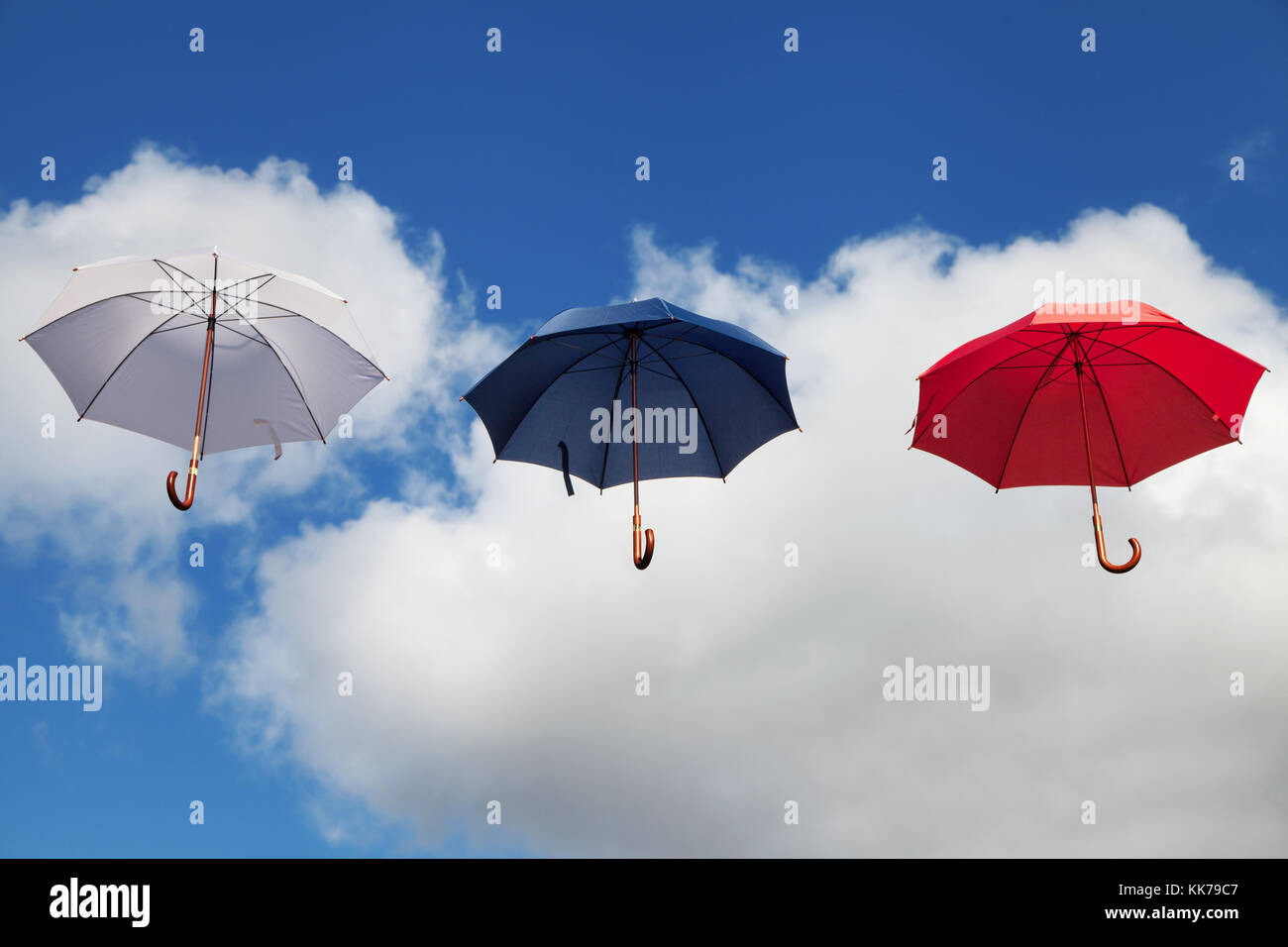 Trois Parapluies flottantes en blanc, bleu foncé et rouge Banque D'Images