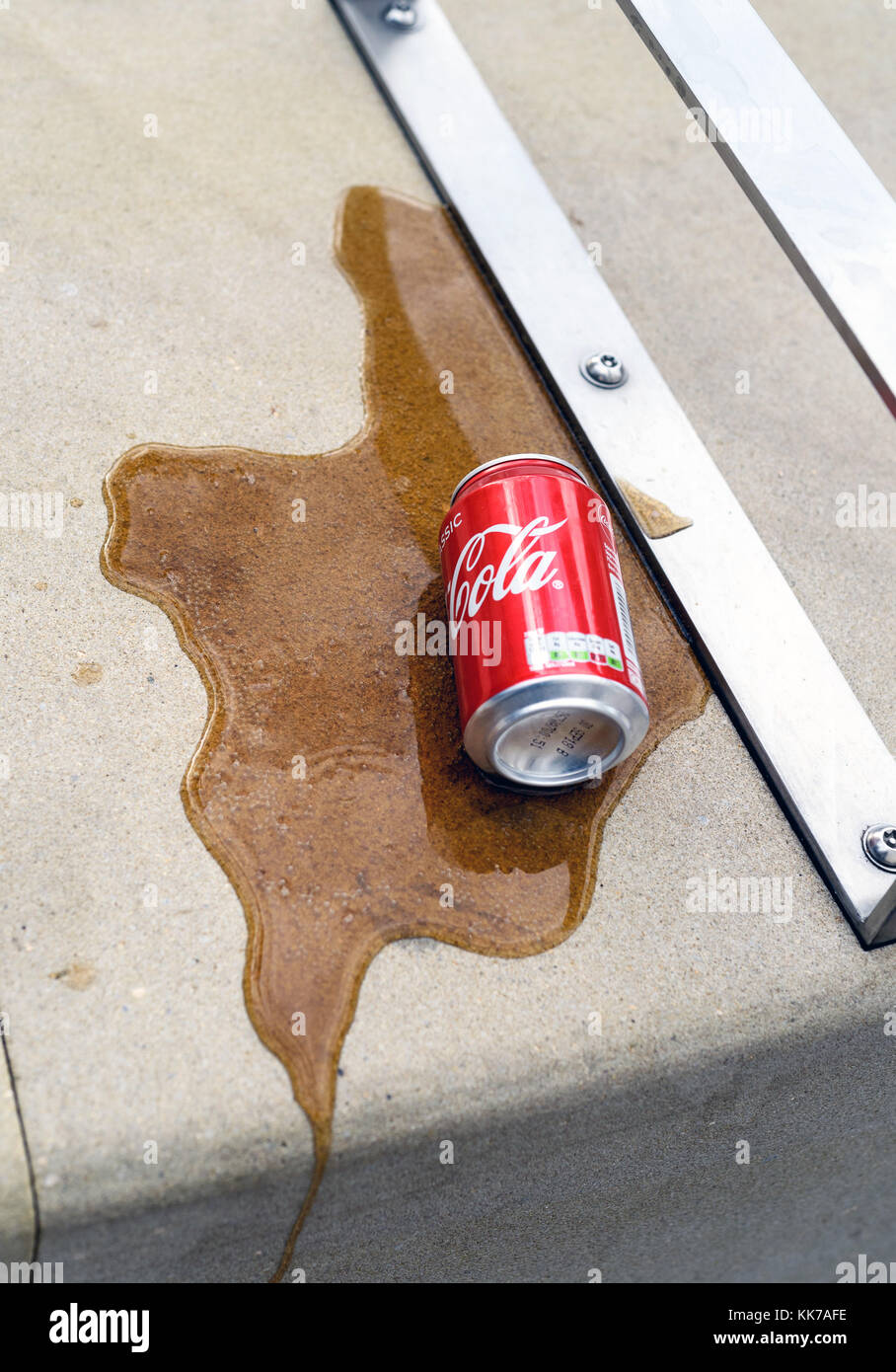 Coke déversés peuvent sur le béton avec un débit de liquide brun cola