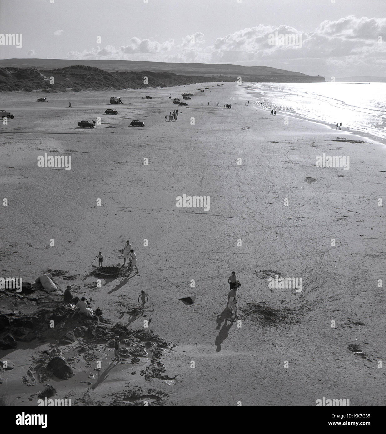 Années 1950, tableau historique, des voitures en stationnement sur la vaste étendue d'une magnifique plage de sable peu fréquentée au nord de l'Irlande du côte de Causeway. Banque D'Images