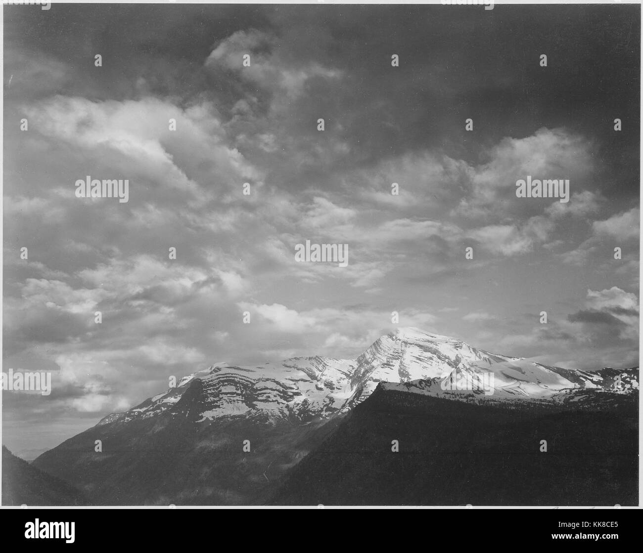 Photographie en noir et blanc, sombre et les nuages d'avant-plan, les montagnes en surbrillance, titré "Heaven's Peak', par Ansel Adams, à partir de photographies des Parcs Nationaux et Monuments, Glacier National Park, Montana, United States, 1941. Banque D'Images