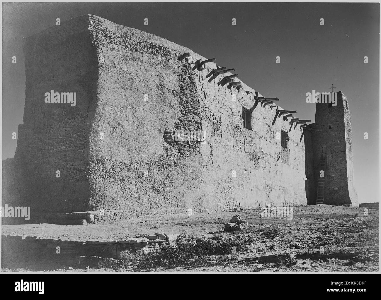 Un extérieur noir et blanc photographie de San Estevan del Rey Mission Church, le bâtiment d'adobe a été construit au 17e siècle, les poutres en bois qui créent la structure de la toiture peut être vu qui dépasse de l'autre, une croix se dresse sur la tour à l'angle, l'image provient d'une série de photographies connu comme le projet mural par Ansel Adams, il a été commandé par le National Park Service en 1941 pour créer une fresque photographique pour le ministère de l'intérieur des capacités à Washington DC, le projet a pris fin en raison de la Seconde Guerre mondiale, l'église fait partie d'Acoma Pueblo et a été inha Banque D'Images