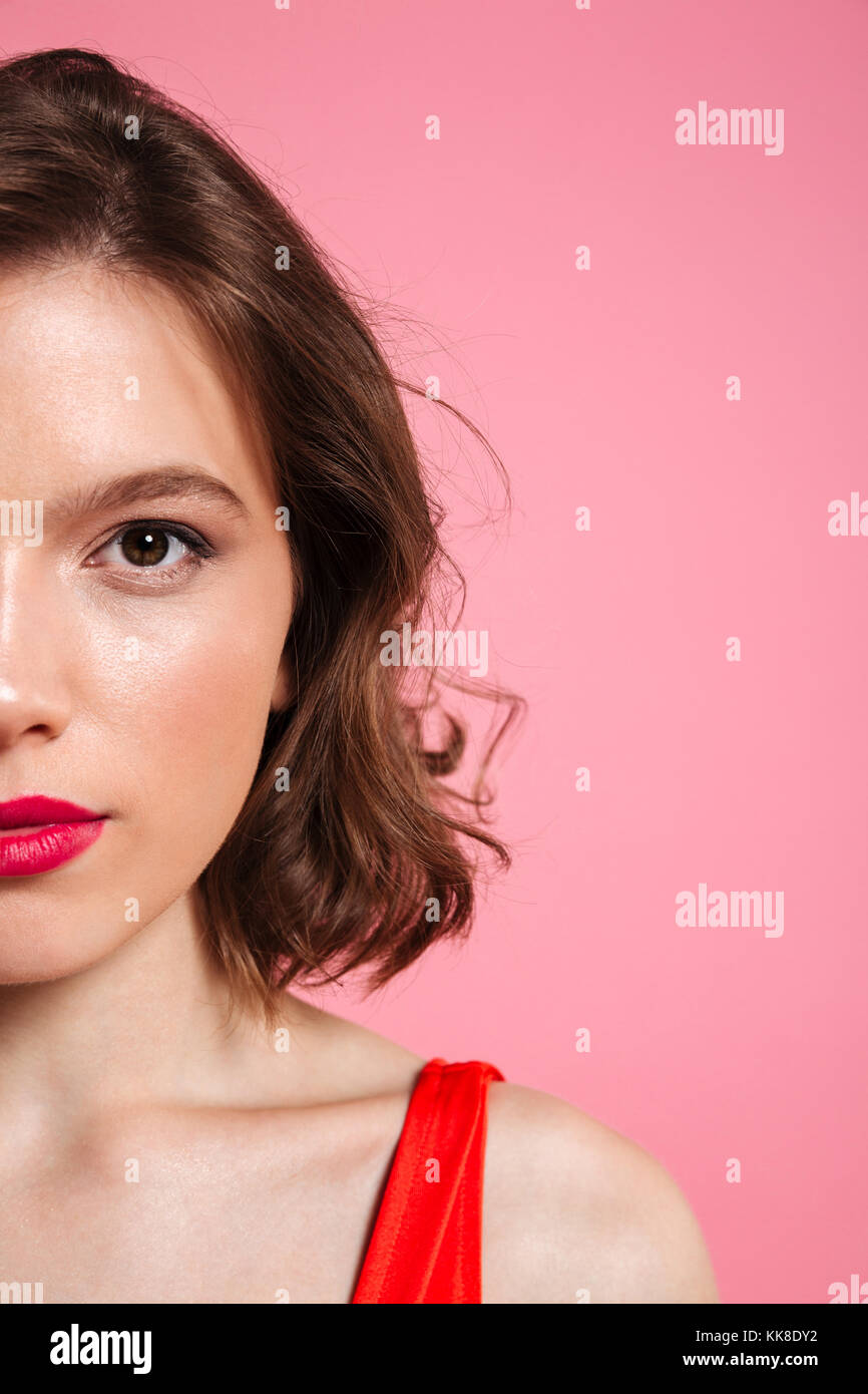 Photo recadrée de cheerful young woman with red lips looking at camera, isolé sur fond rose Banque D'Images