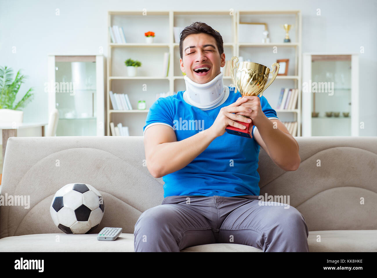 Homme avec blessure au cou à regarder à la maison football soccer Banque D'Images