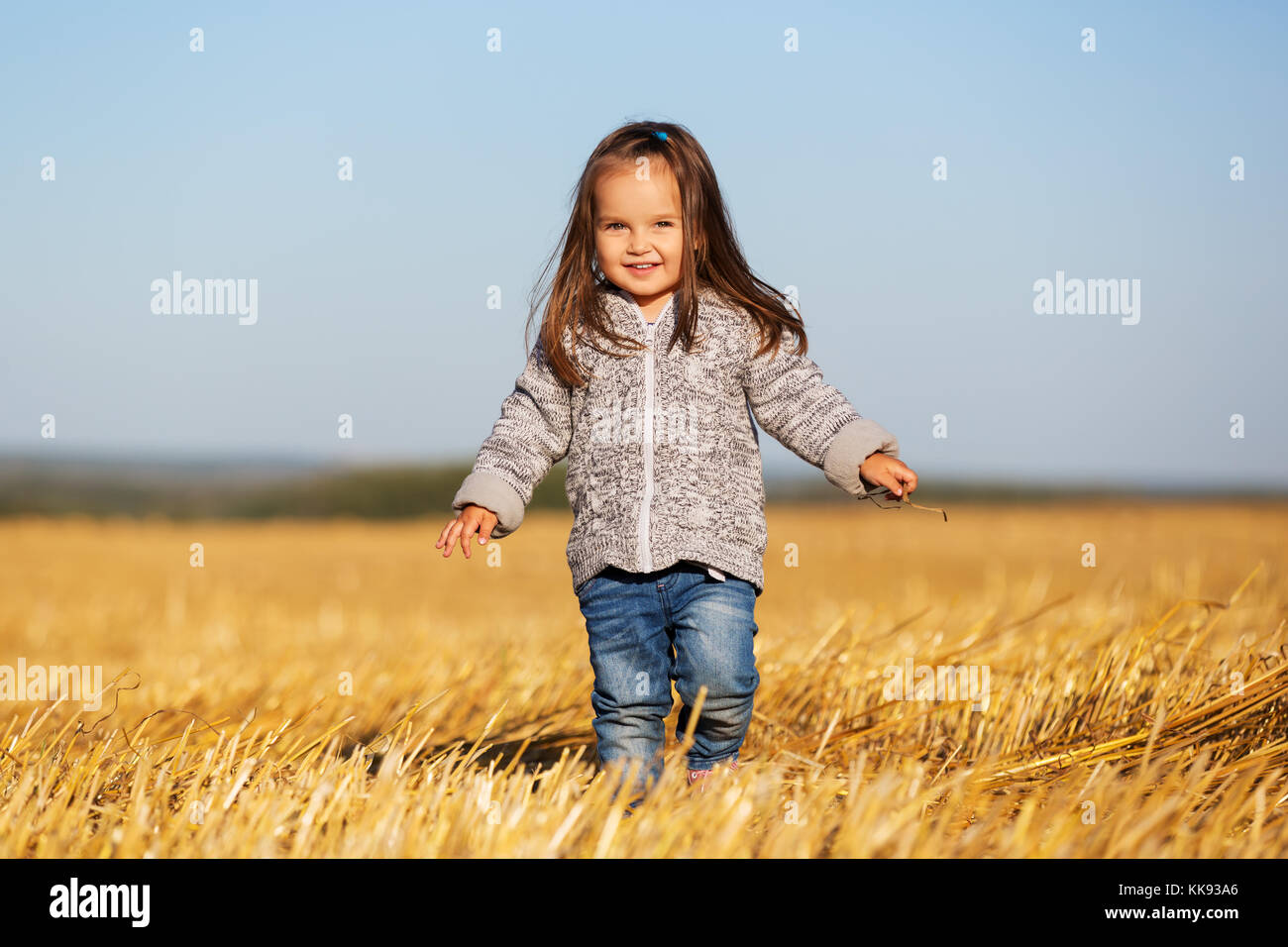 Happy 2 ans, fille de marcher dans un champ récolté l'été Banque D'Images