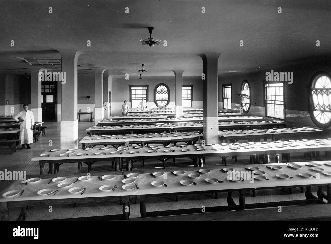 Photographie en noir et blanc de la salle à manger sur l'île Ellis, assiettes et couverts disposés sur de longues tables, par Edwin Levick, Ellis Island, New York, 1907. À partir de la Bibliothèque publique de New York. Banque D'Images