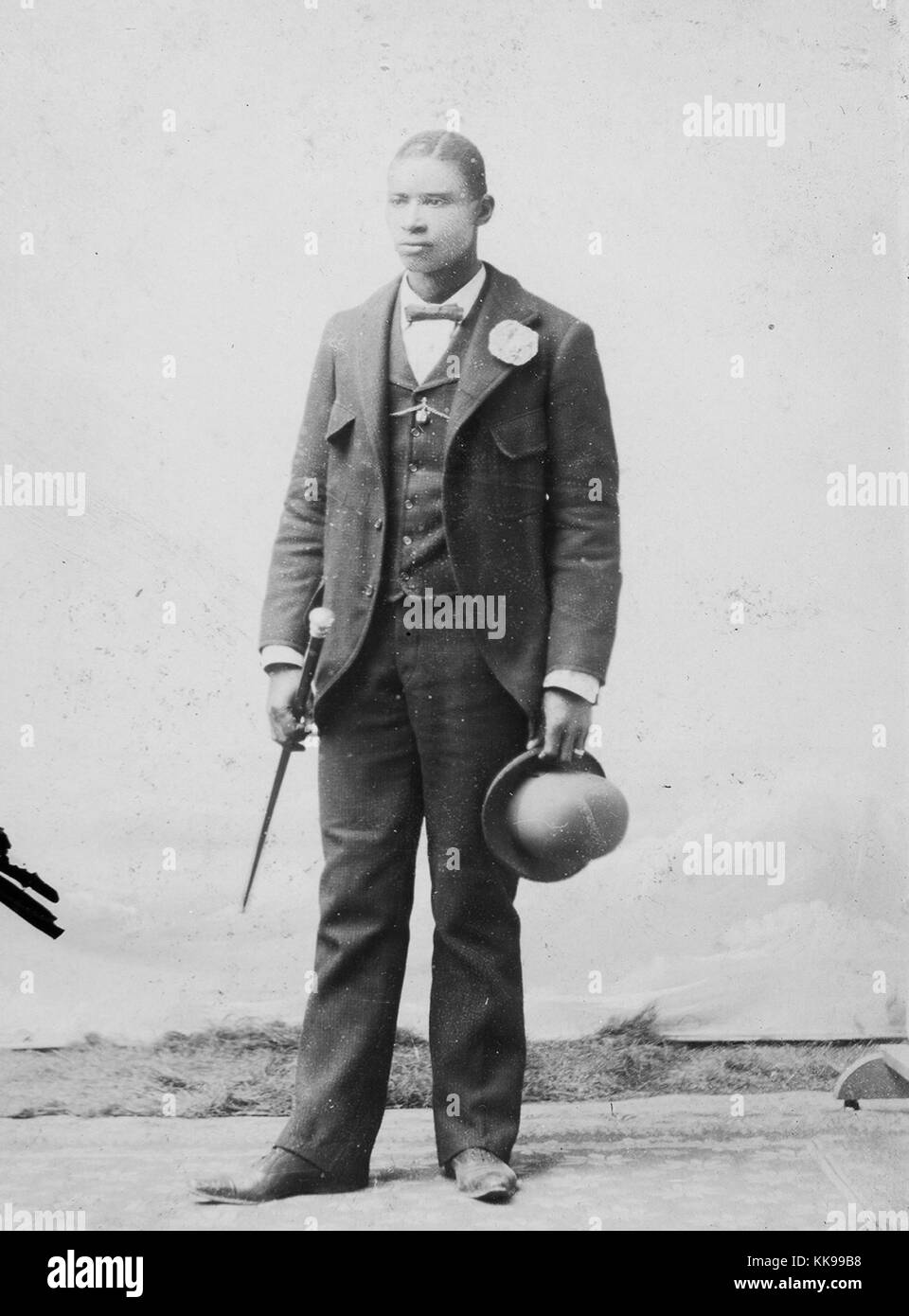 Sepia studio portrait d'un homme afro-américain, pleine longueur, d'un costume, tenant un chapeau melon et canne à sucre, 1900. À partir de la Bibliothèque publique de New York. Banque D'Images