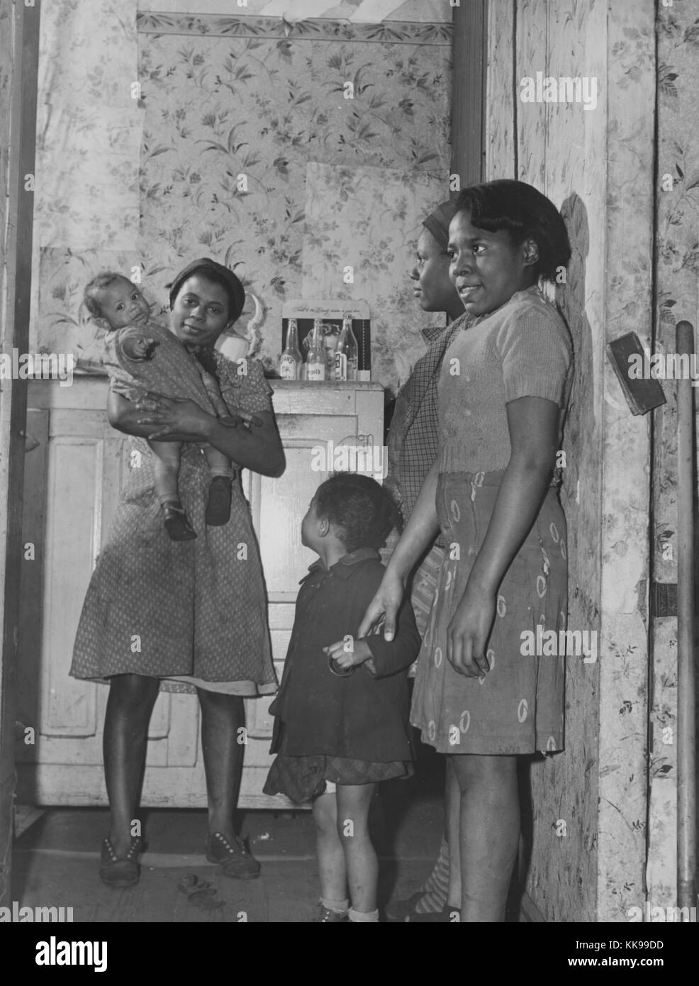 Photographie en noir et blanc de trois jeunes Afro-Américaines debout dans le couloir d'une maison, l'une tenant un bébé, une jeune fille avec eux, à Norfolk, Virginie, Mars, 1940. À partir de la Bibliothèque publique de New York. Banque D'Images