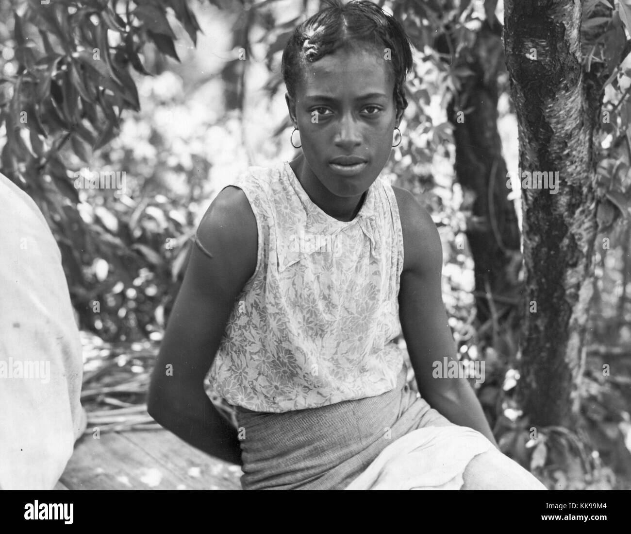 Photographie en noir et blanc d'une jeune femme afro-américaine assis sous un arbre, marquée 'hoer', Clarksdale, Mississippi, en juin, 1937. À partir de la Bibliothèque publique de New York. Banque D'Images