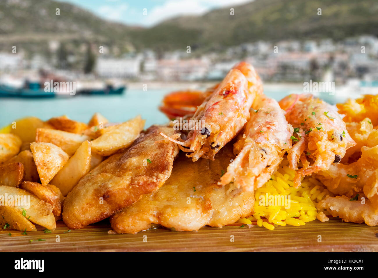 Plateau de poisson avec du poisson frit,calamaris et gambas grillées. comme accompagnement servi riz au curry et frites agriculteur. l'arrière-plan montre un pittoresque fisherm Banque D'Images