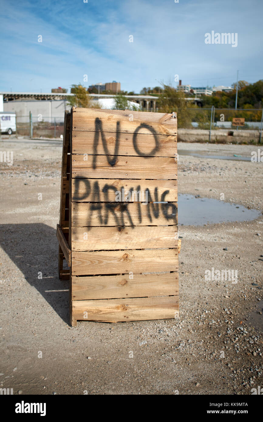 Pas de parking en bois peint à la bombe sur un châssis a signer, debout au milieu d'un parc de stationnement ouvert avec des flaques d'eau Banque D'Images