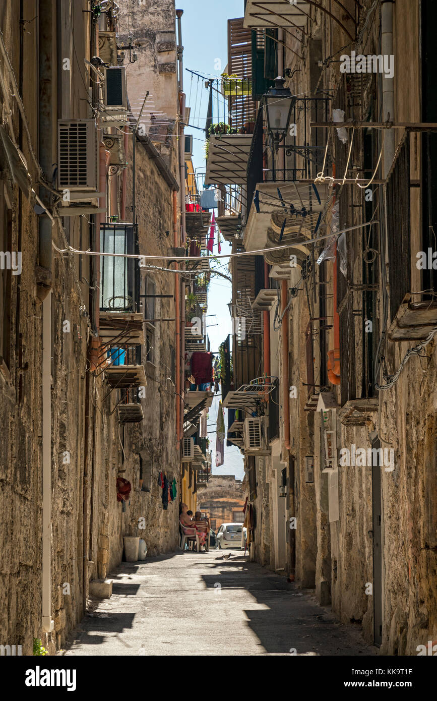En regardant le long d'une étroite rue résidentielle italienne à Palerme, la Sicile avec un homme et une femme s'assit à l'extérieur de leur maison. Banque D'Images