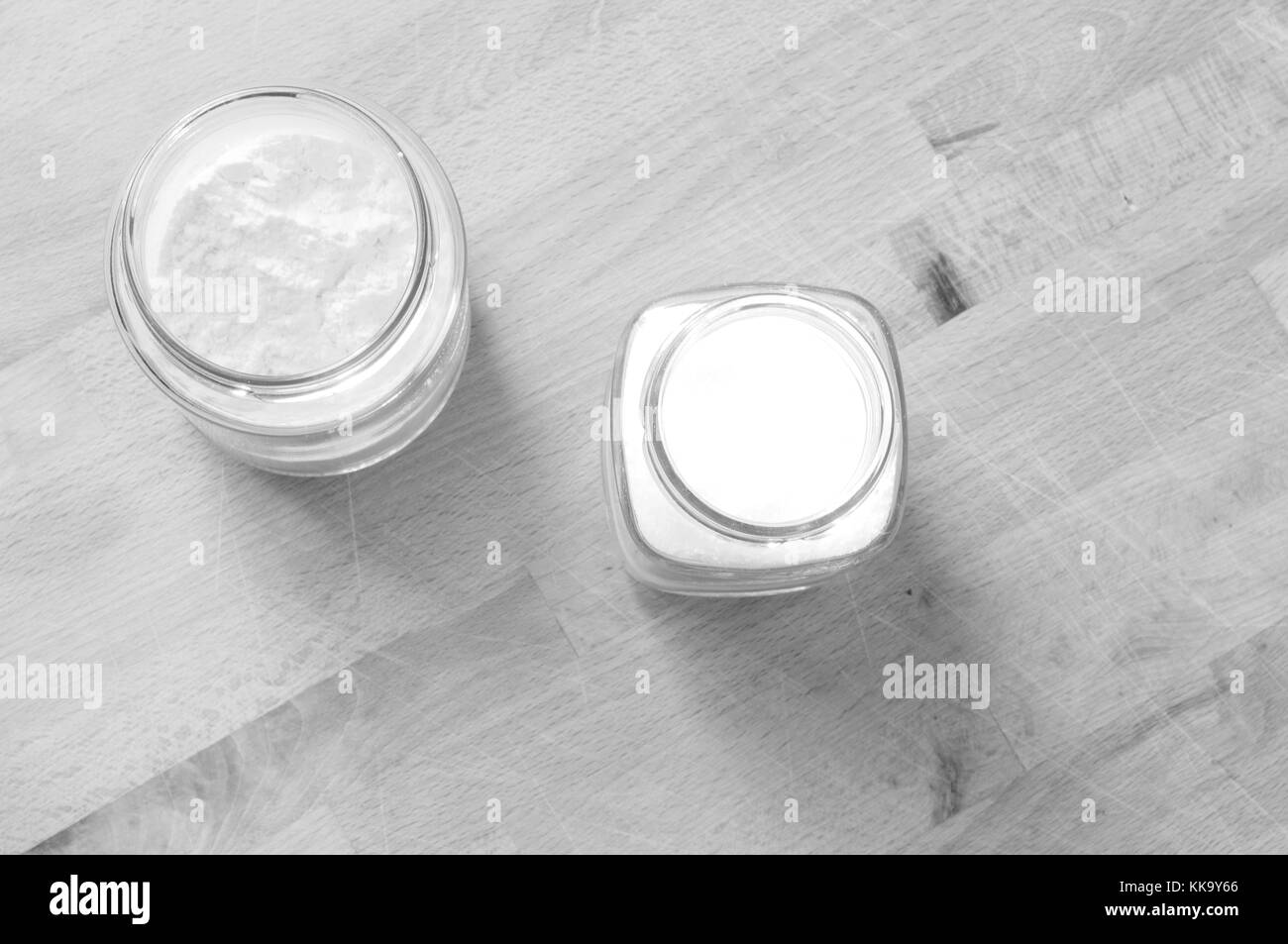 Deux pots en verre soulevées par le dessus avec du sucre et de la farine sur la table de cuisine en bois Banque D'Images