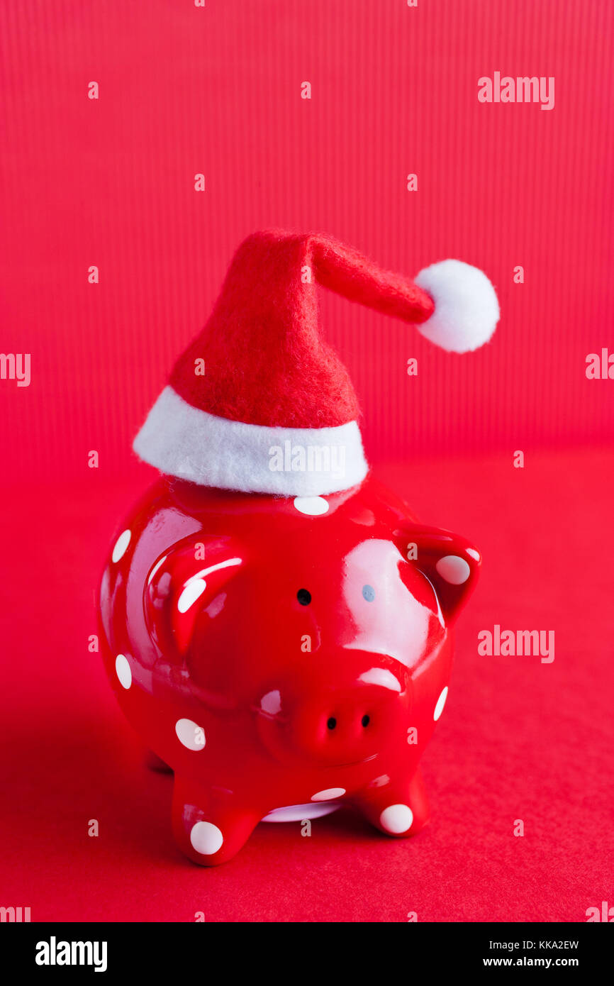 Économies d'argent Red Piggy Bank avec chapeau de Père Noël sur fond rouge - finance et économie - christmass Banque D'Images