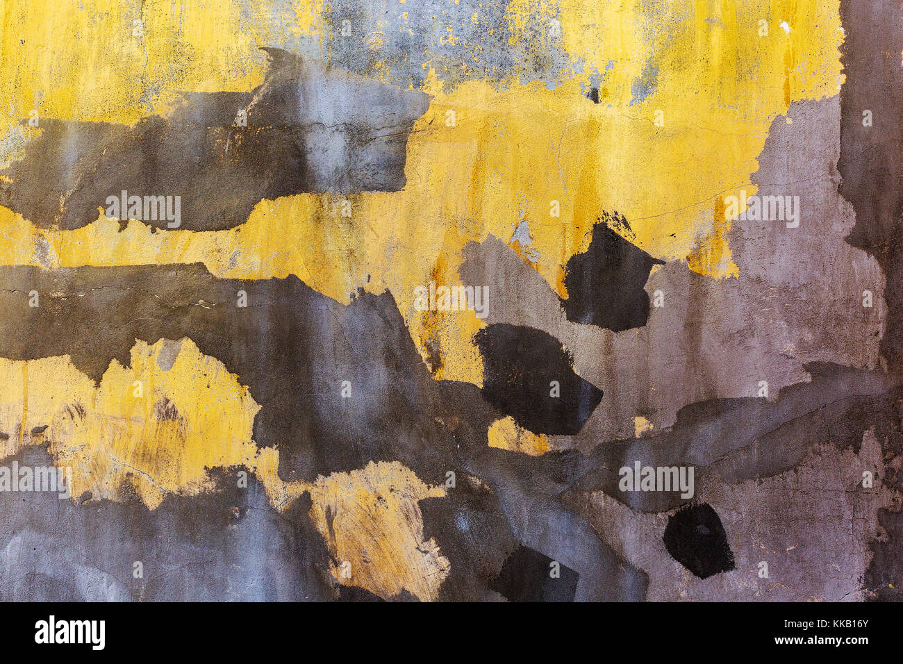 Vieux mur de béton craquelé jaune vif. mur peint avec des points sombres de plâtre. grunge background Banque D'Images