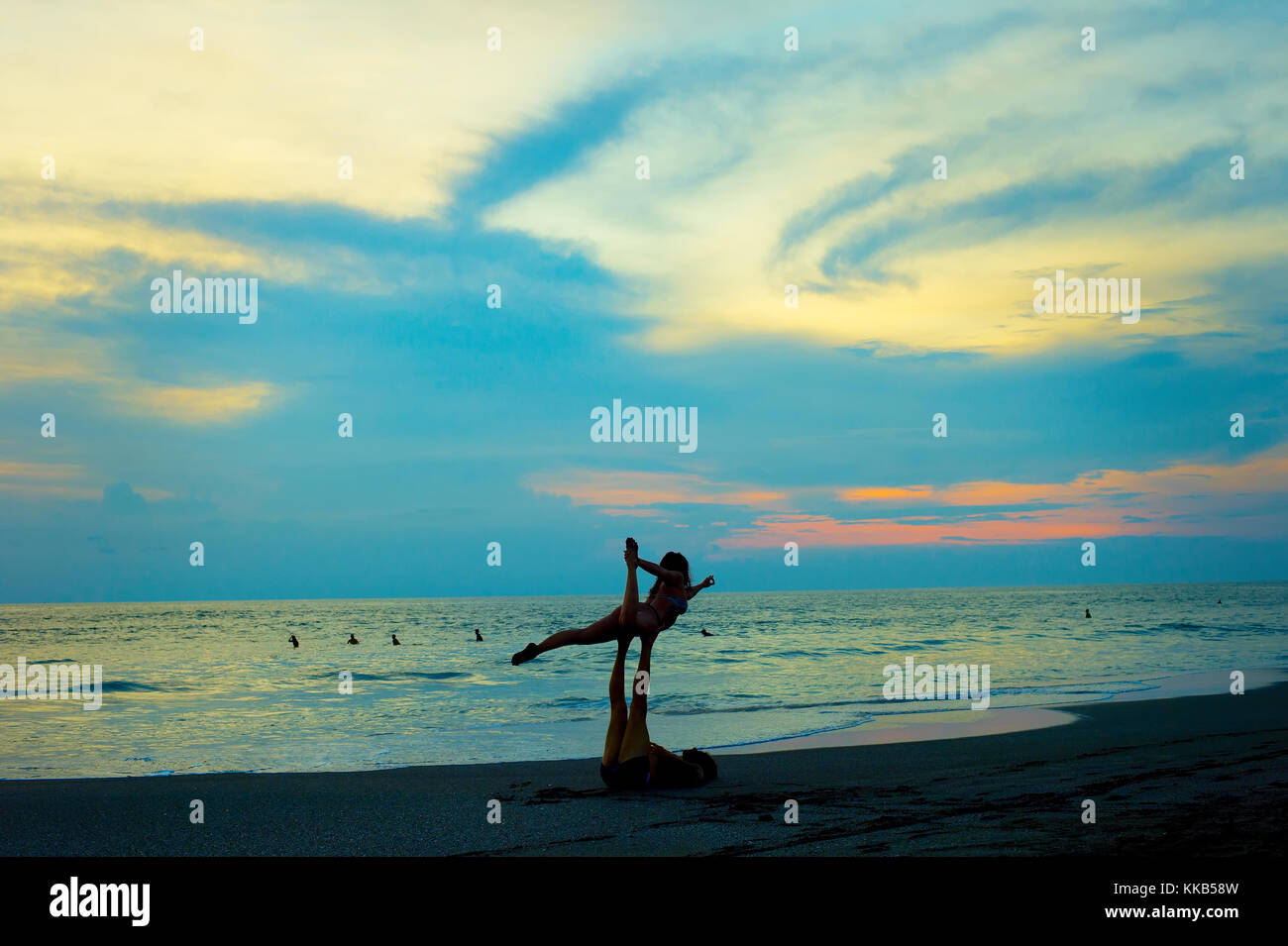 Couple pratiquer le yoga sur la plage au coucher du soleil. L'île de Bali, Indonésie Banque D'Images