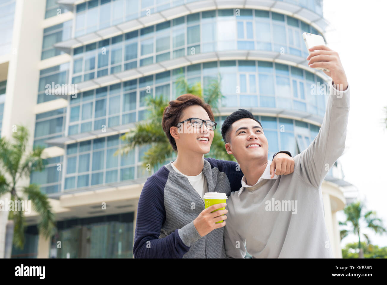 Deux jeunes hommes d'affaires gais et permanent en tenant en selfies office Banque D'Images
