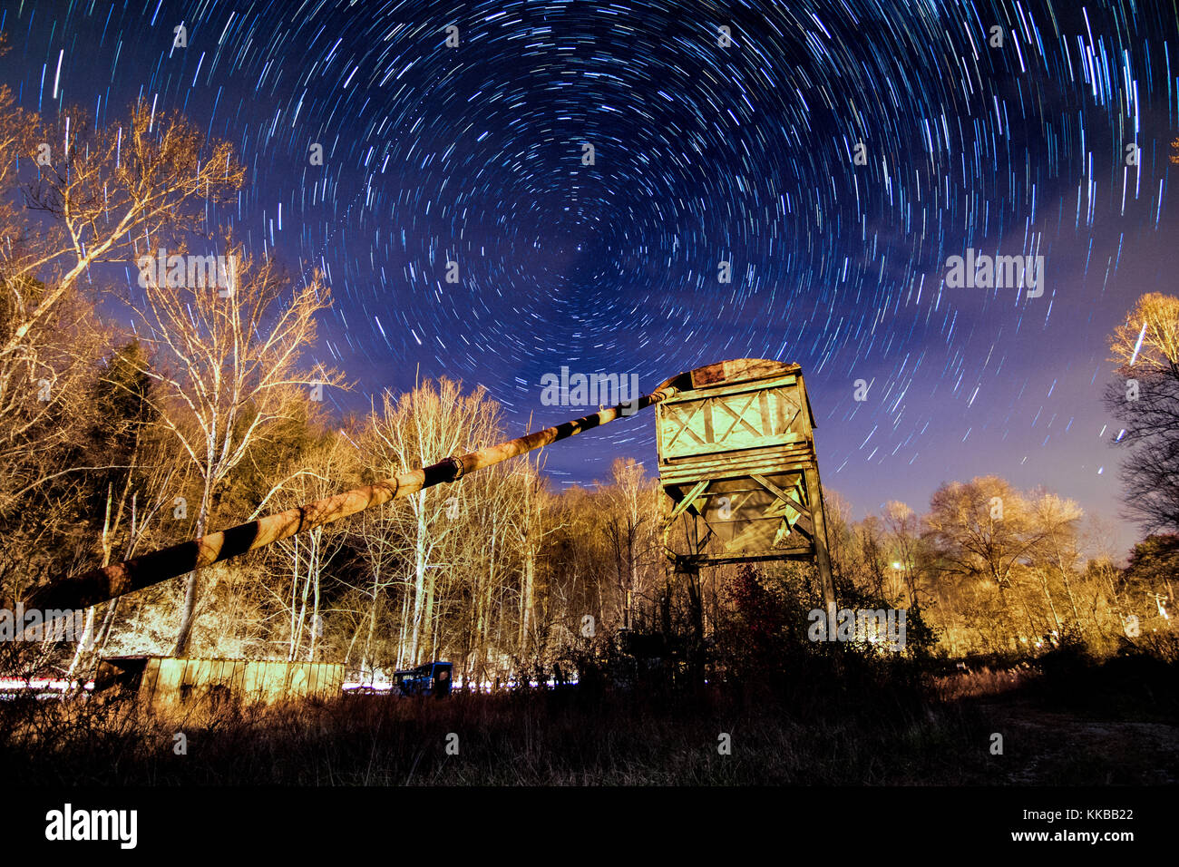Cette longue exposition image montre star trails dans le ciel nocturne au-dessus d'une scène industrielle. Banque D'Images