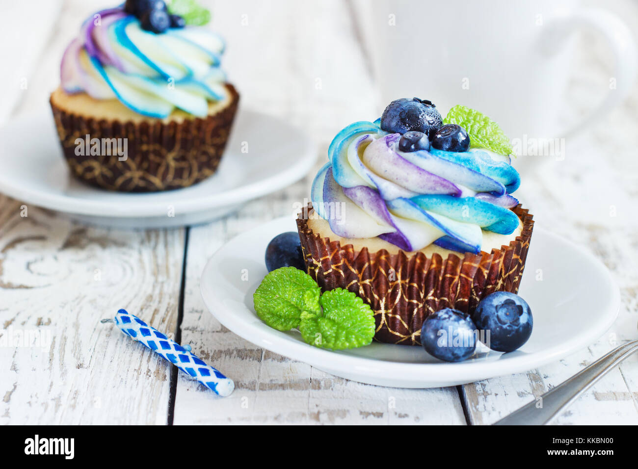 Cupcakes vanille délicate avec de la crème et des petits fruits les bleuets sur un fond de bois blanc. Banque D'Images