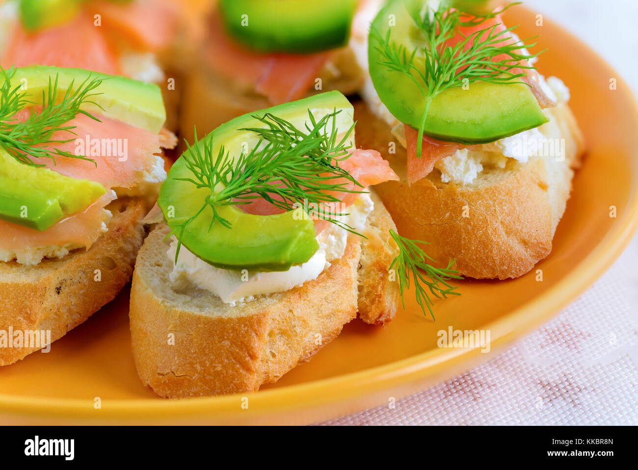 Bruschetta, snack-sandwiches avec du fromage blanc, saumon fumé et morceaux d'avocat décoré par de l'aneth. Banque D'Images