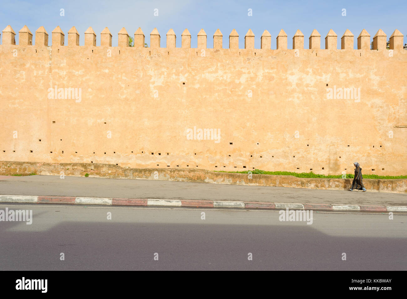 Femme marche par un ancien mur de la ville Banque D'Images