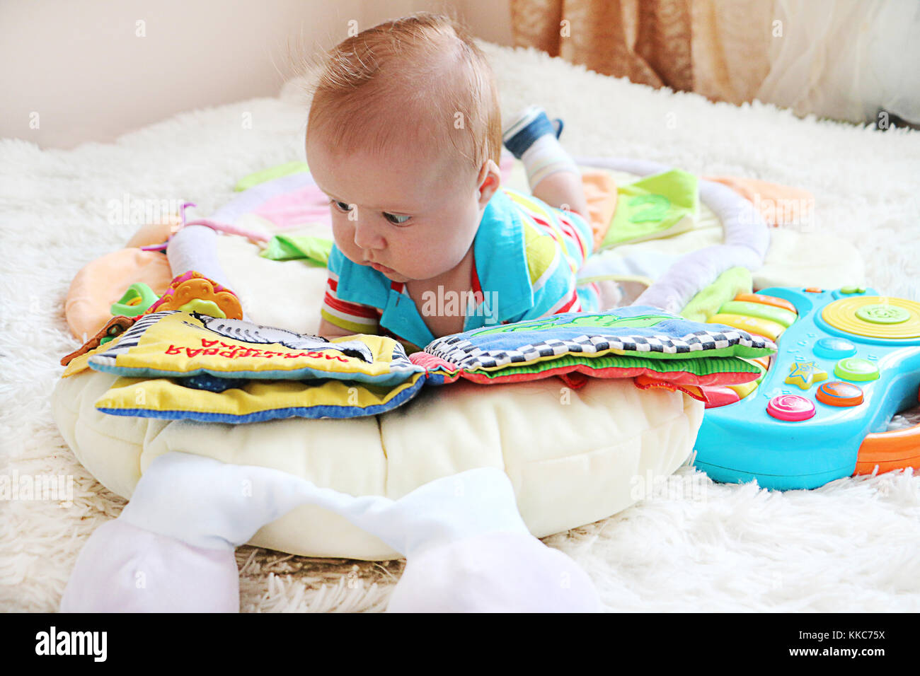 Mignon petit bébé avec les yeux bleus et cheveux gingembre lire un livre sur le lit. Banque D'Images
