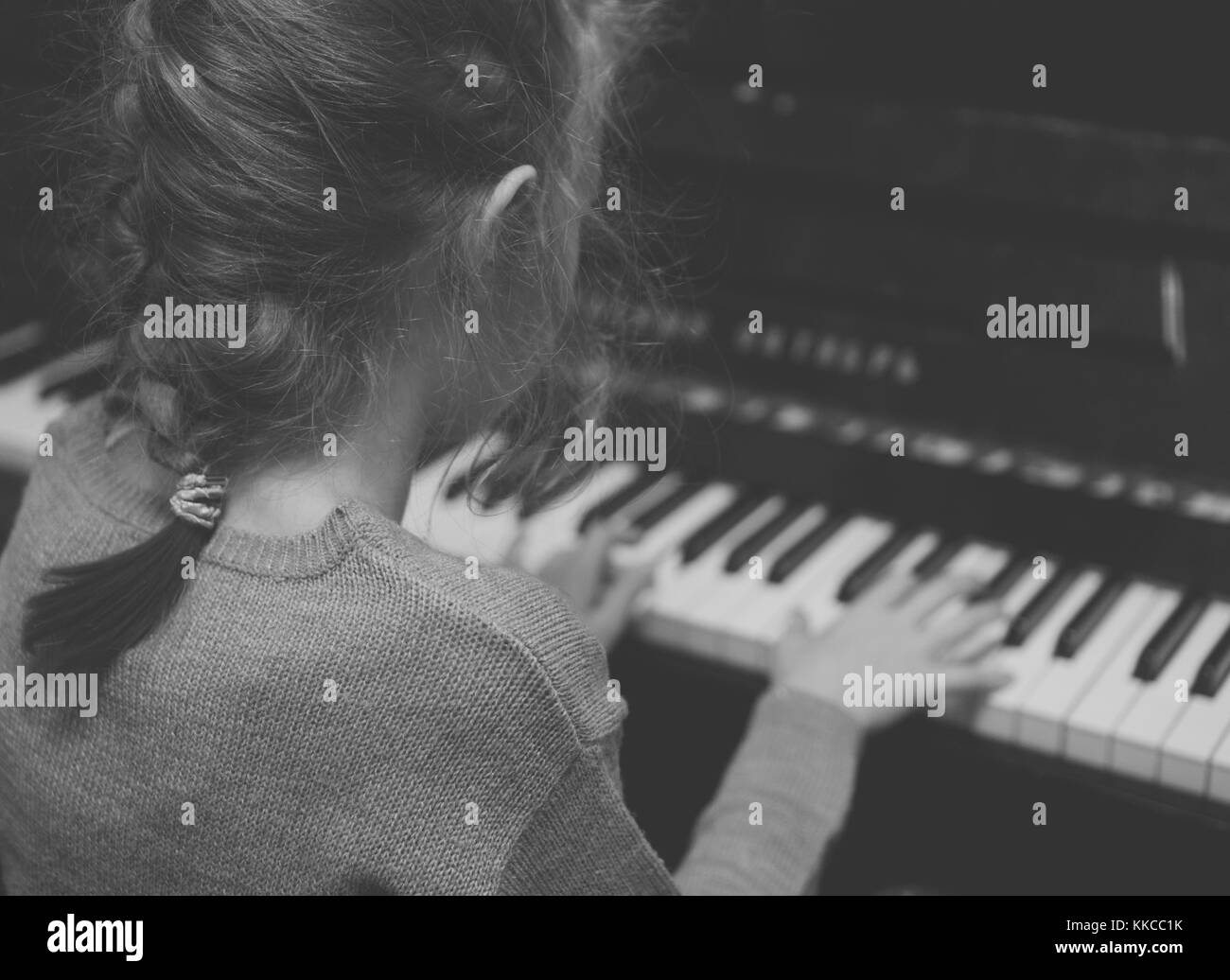 Petite fille apprenant à jouer du piano. Noir et blanc. Banque D'Images