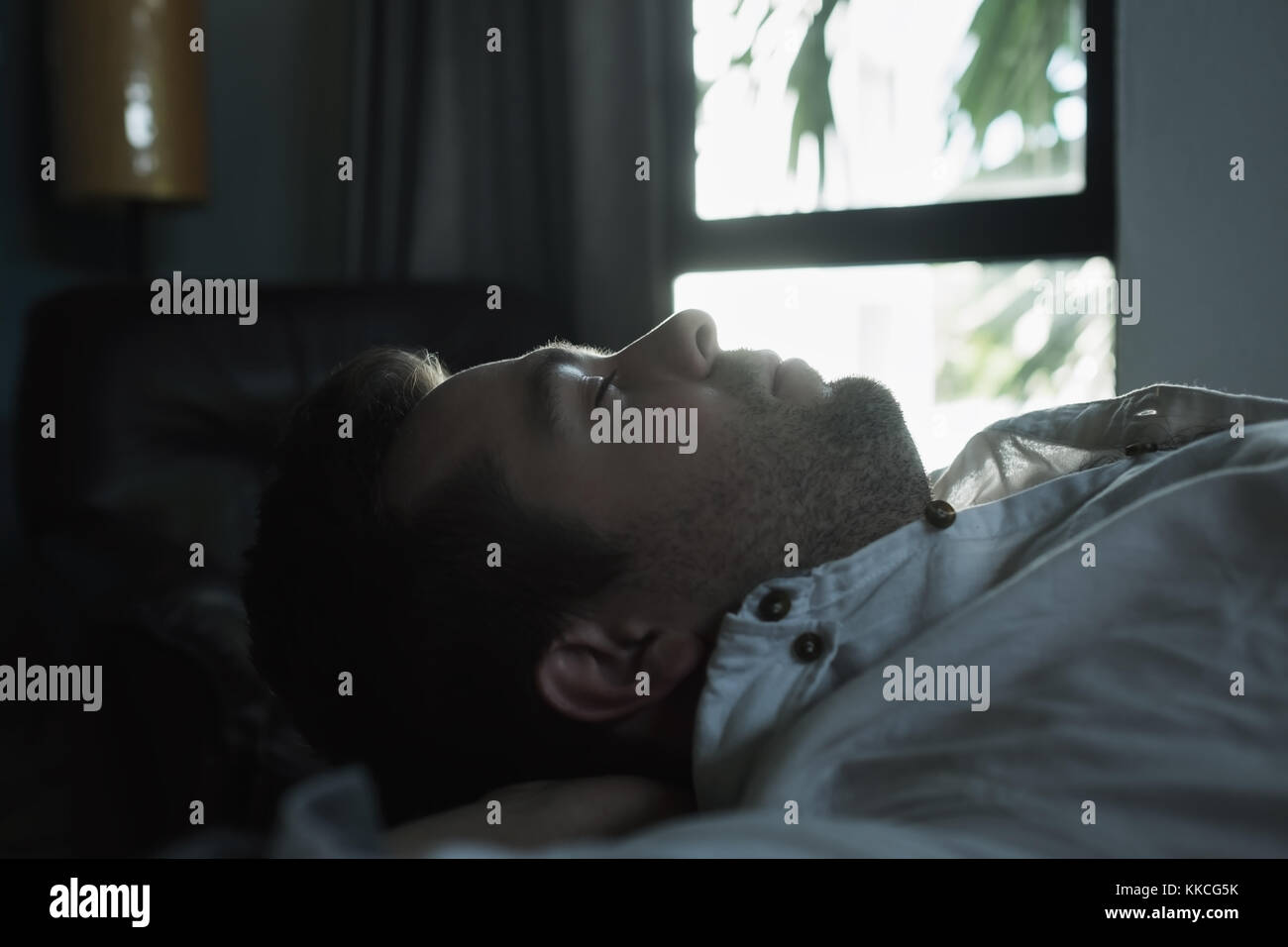 Portrait d'un jeune homme de race blanche au-dessus de dormir dans une chambre sombre. Banque D'Images