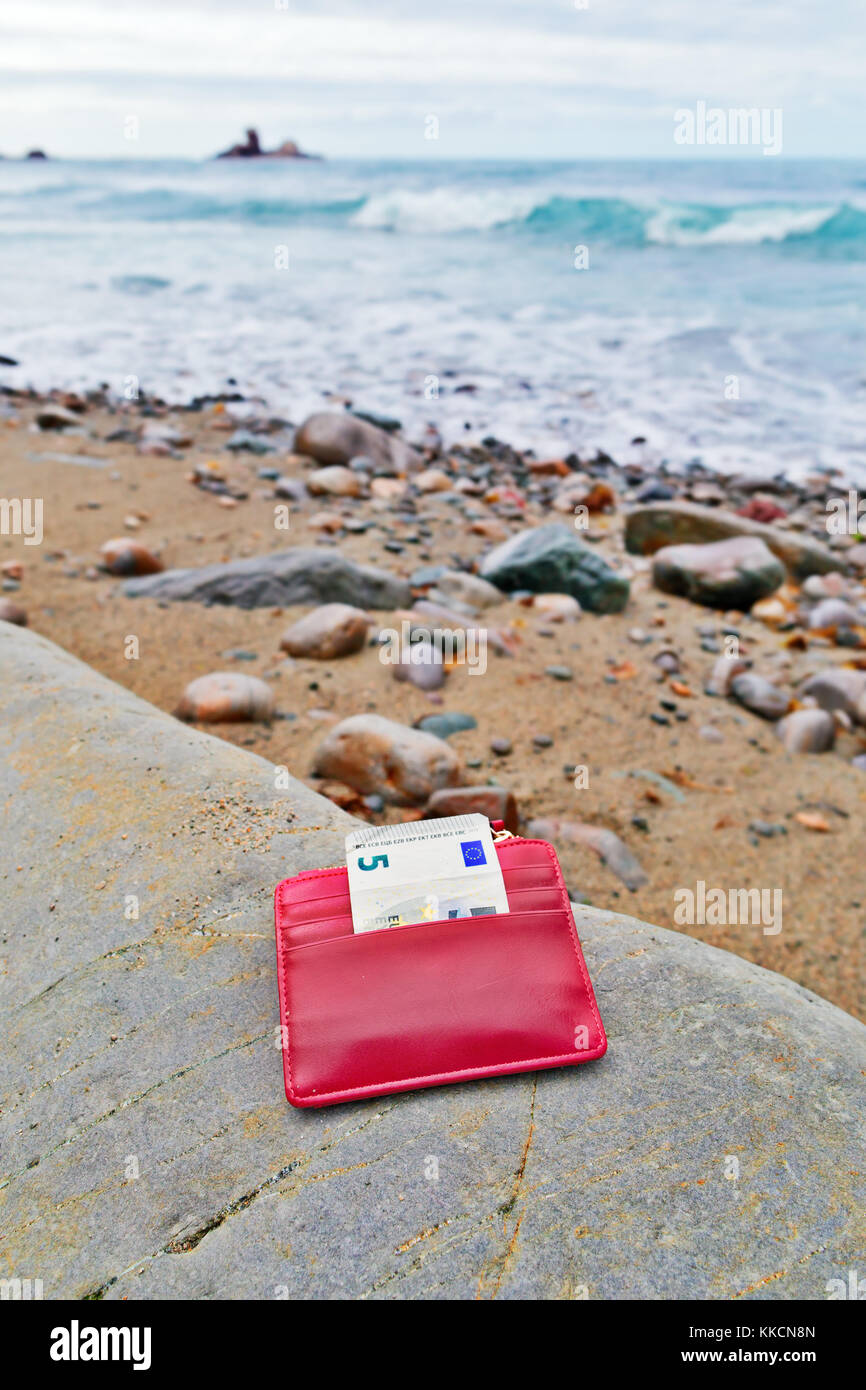 Le Trésor perdu sur le bord de la mer. La plage de galets, un petit sac à main rouge avec la remarque de cinq euros Banque D'Images