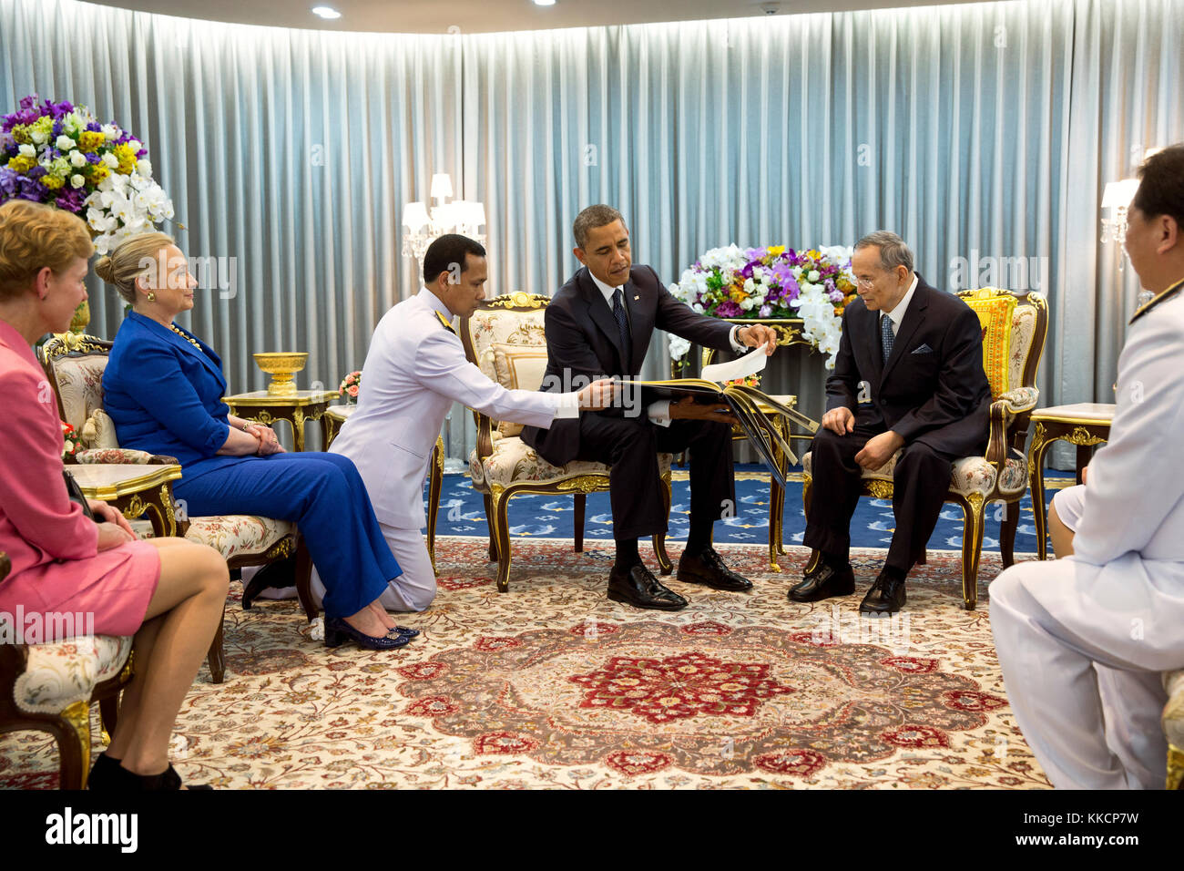 Le président barack obama présente un cadeau pour le roi Bhumibol Adulyadej de Thaïlande au cours de leur rencontre à hôpital Siriraj à Bangkok, Thaïlande, nov. 18, 2012. Le président Obama a présenté un album photo contenant des photos du roi avec des présidents des États-Unis et premières dames datant le président Eisenhower. ambassadeur des États-Unis en Thaïlande Kristie Kenney avec le secrétaire d'État américaine Hillary Rodham Clinton sont assis à gauche. (Photo Officiel de la maison blanche par Pete souza) officiel de la maison blanche cette photographie est mis à disposition uniquement pour la publication par les entreprises de presse et/ou pour un usage personnel l'impression par le s Banque D'Images