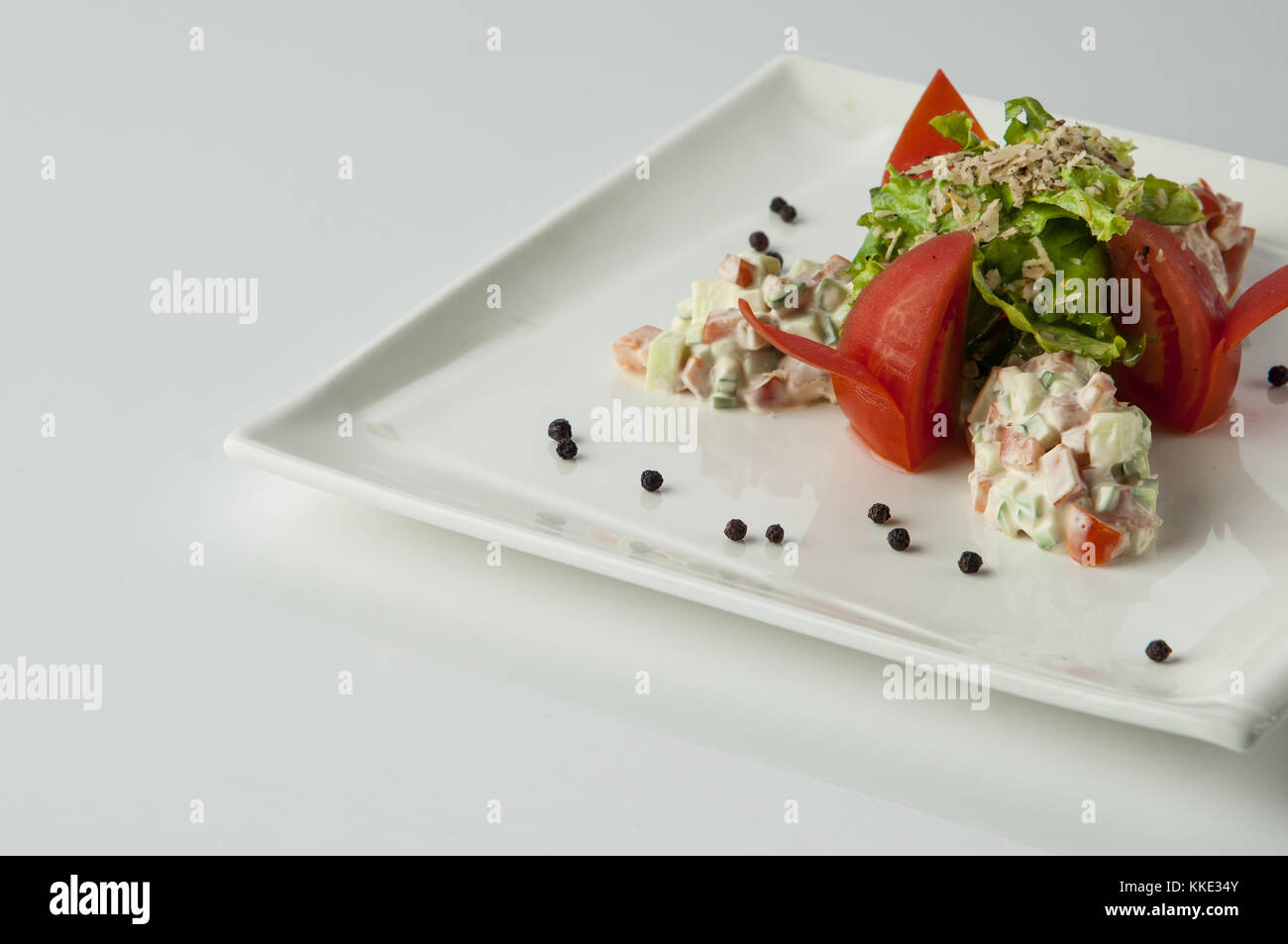 Avec la salade et la mayonnaise tomate dans une assiette sur un fond blanc Banque D'Images