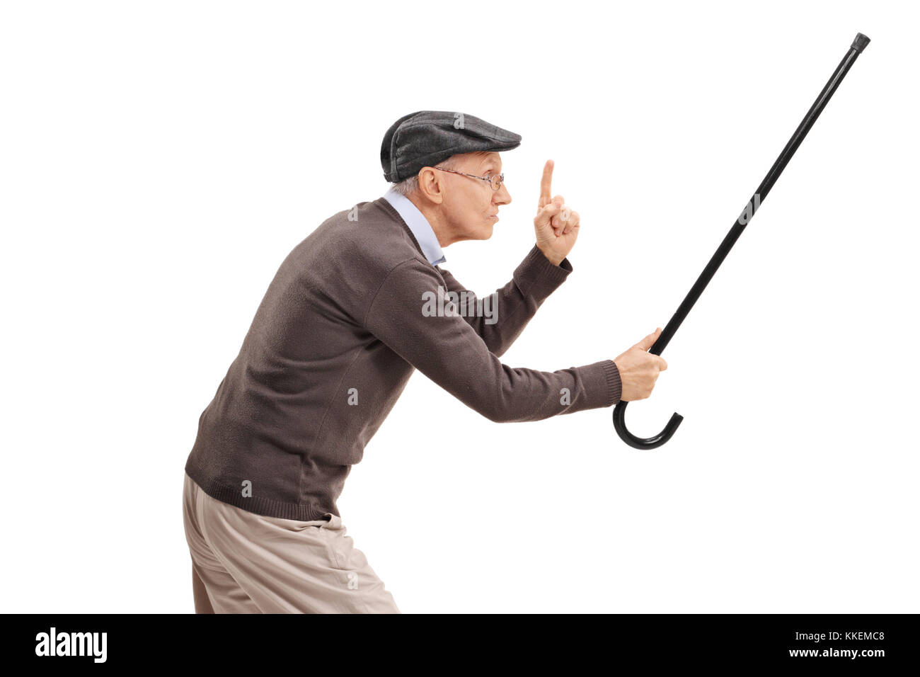 Senior en colère holding sa canne comme un sabre et gesticulant avec son doigt isolé sur fond blanc Banque D'Images