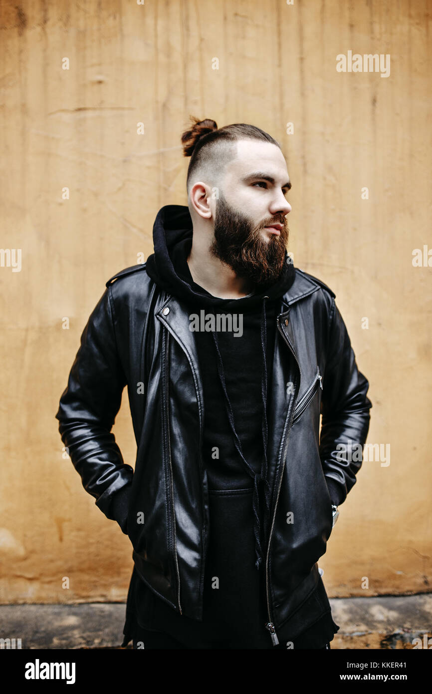 Jeune homme barbu moderne en noir vêtements de style debout dans autour d'origine urbaine. Banque D'Images