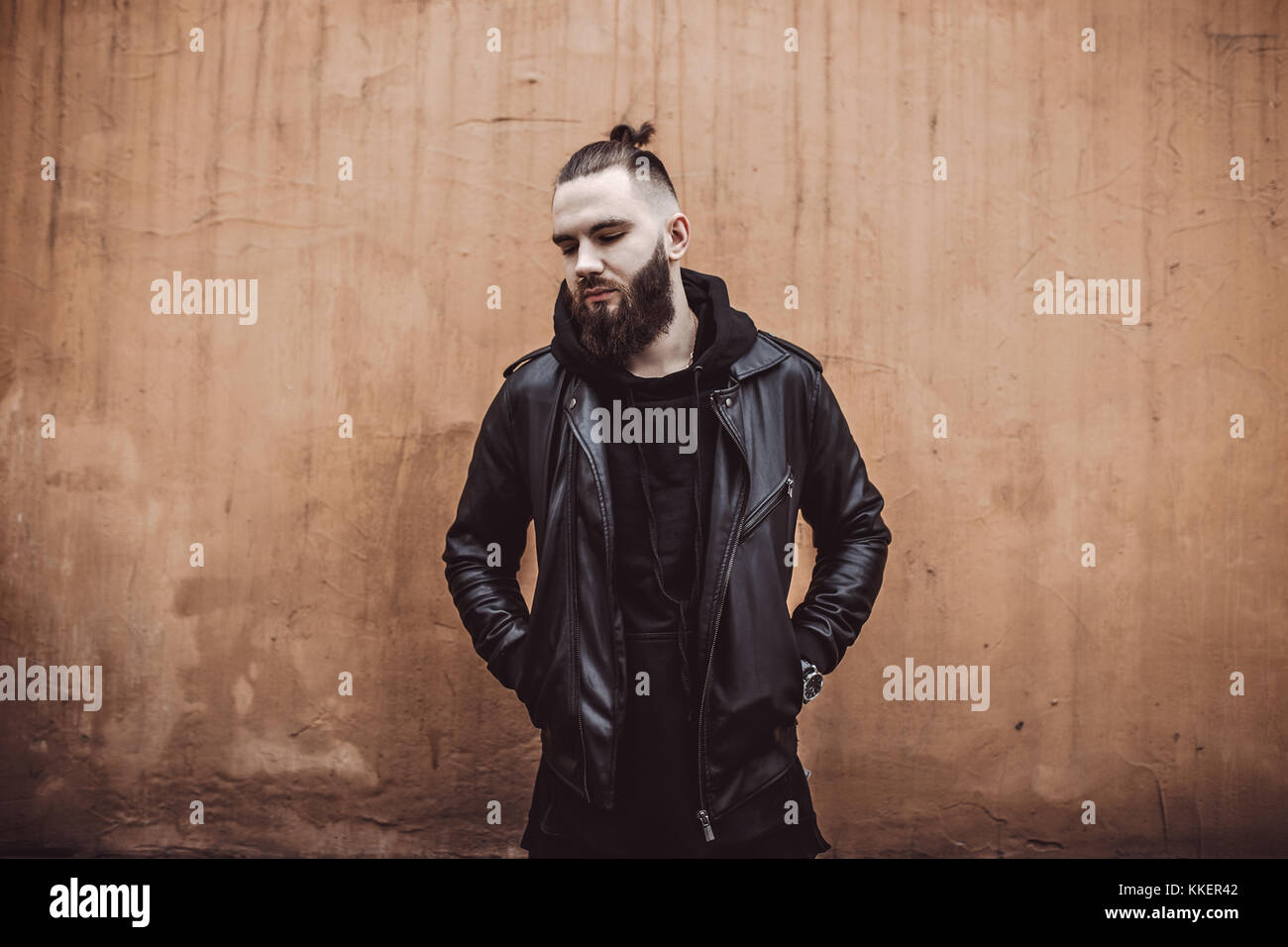 Jeune homme barbu moderne en noir vêtements de style debout dans autour d'origine urbaine. Banque D'Images Jeune homme barbu moderne en noir vêtements de style debout dans autour d'origine urbaine. Banque D'Images