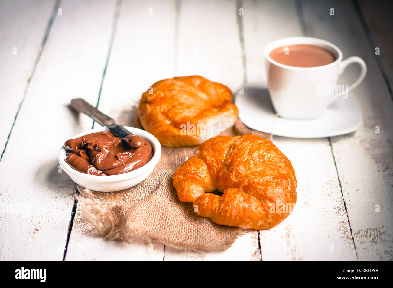 Des croissants frais avec crème au chocolat et chocolat chaud sur fond de bois Banque D'Images