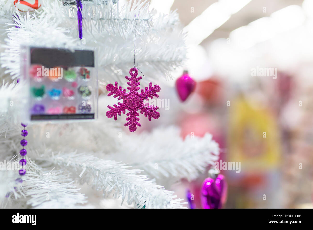 Snowflak pourpre décorations babiole et accroché à un arbre de Noël blanc dans la vitrine d'un magasin du centre commercial au Royaume-Uni Banque D'Images