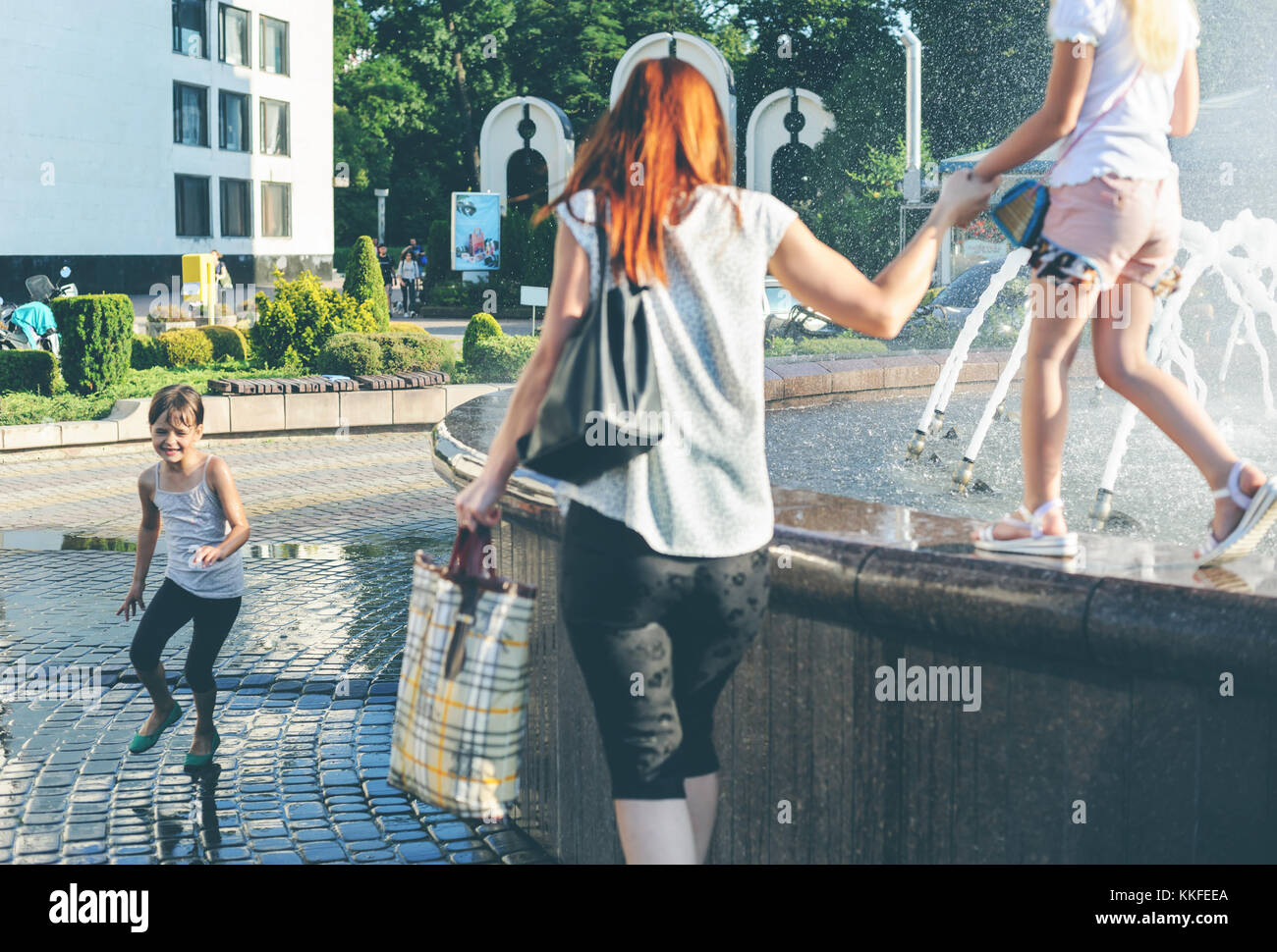 Ivano Frankivsk ukraine, 18 juin 2017. Une fille est runing autour de la fontaine. Une autre fille est de marcher le long du bord de la tenue de la main de sa mère. Banque D'Images