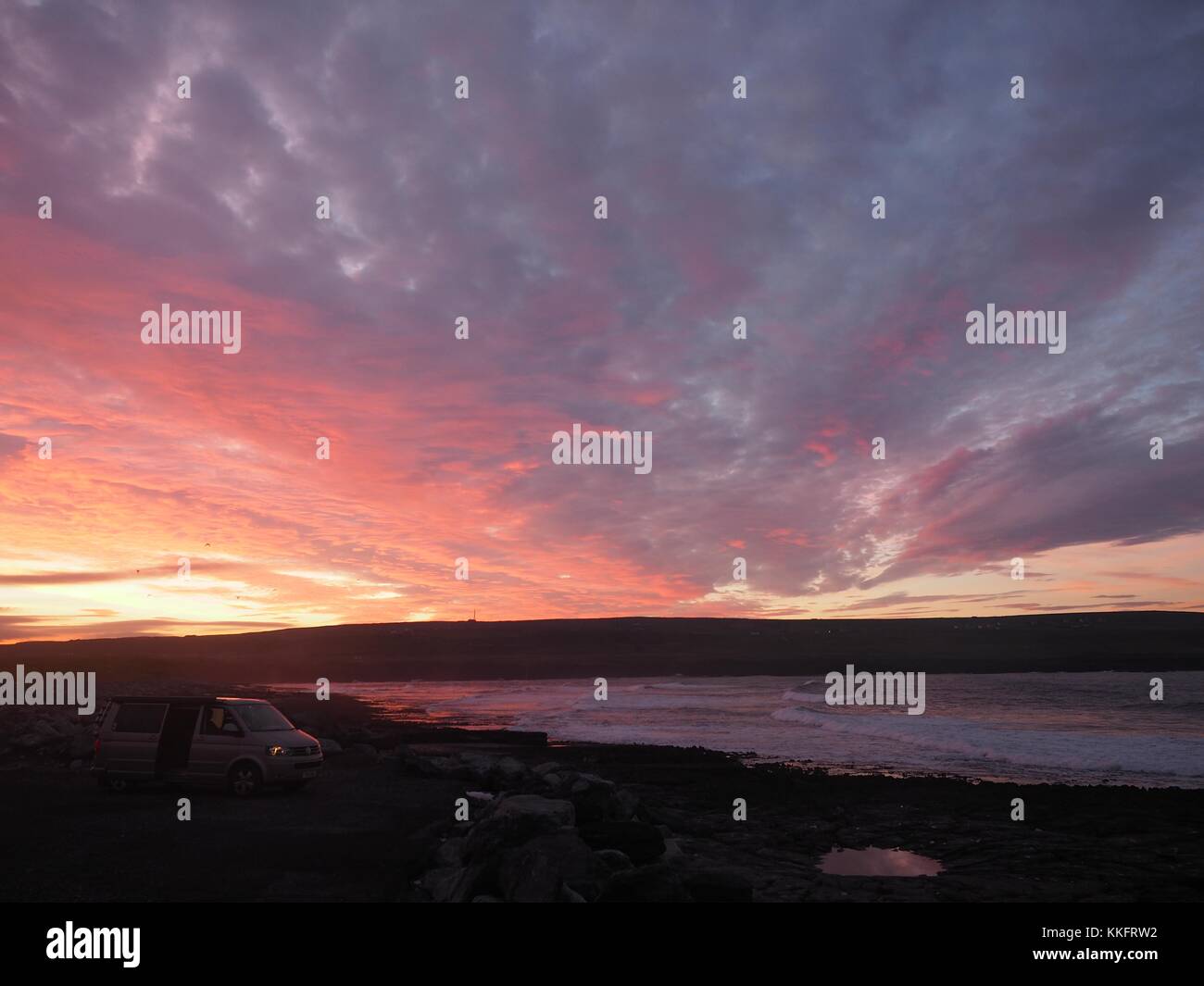 Le soleil se lève sur la façon sauvage de l'Atlantique à Doolin Pier, comté de Clare, Irlande le tournant rock pools un sunburst rouge. Banque D'Images