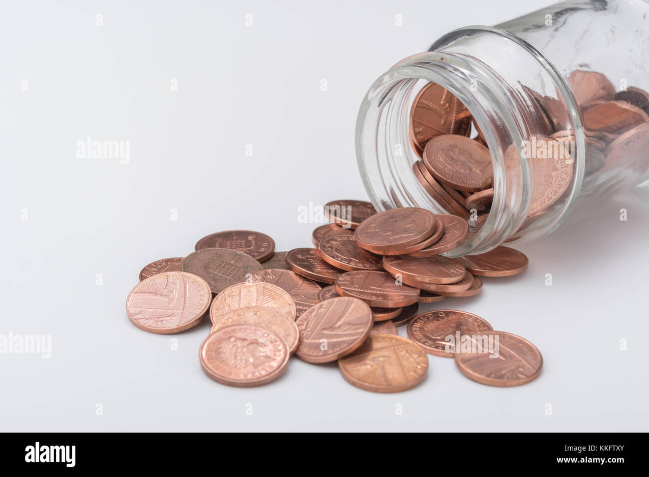 Quelques sous de cuivre à partir de UK en cascade pot en verre. Enregistrement de pièces d'argent, table de cuisine, s'occuper des pennies, Pennywise, l'épargne, 1p défi penny Banque D'Images