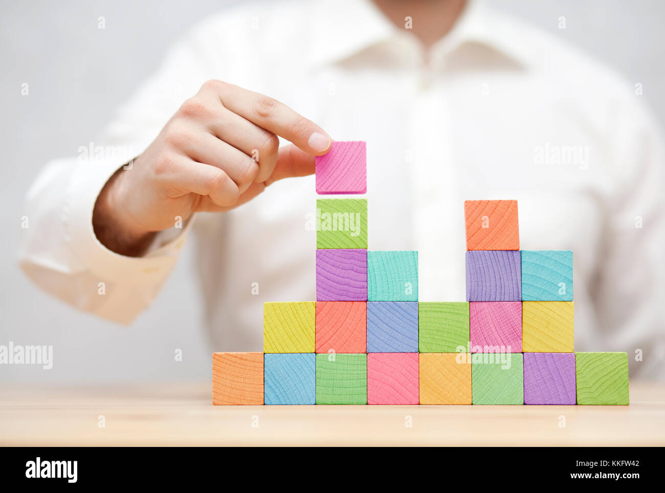 La main de l'homme l'empilement des blocs en bois coloré. business development concept Banque D'Images