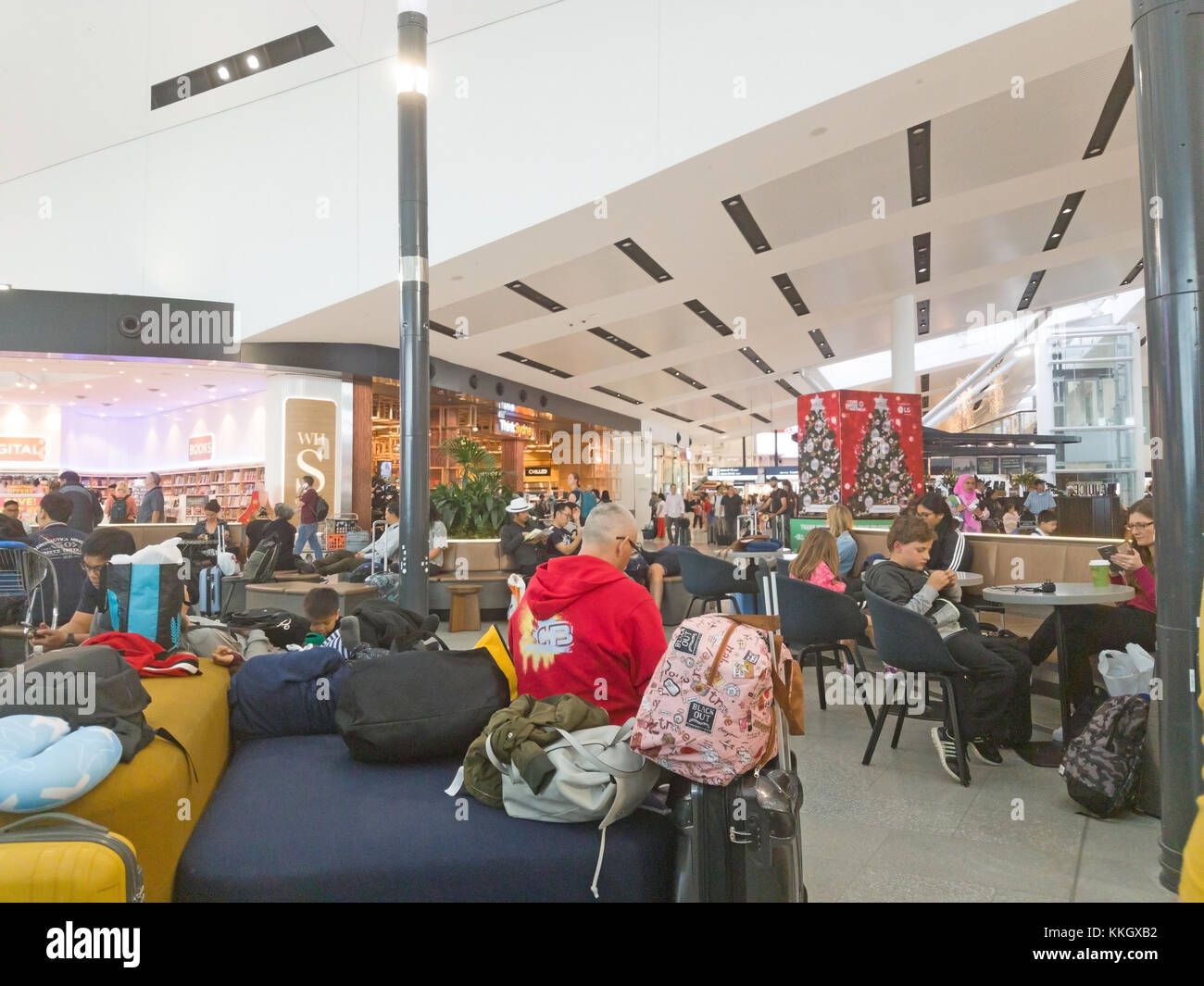 Sydney, Australie - Novembre 27, 2017 ; les gens assis autour de tables et chaises lounge cafe tête en bas à l'aide d'appareils avec les bagages éparpillés dans ai Banque D'Images