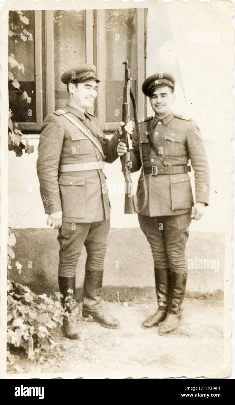 Ion Lupaè™eanu et son compagnon, tous deux photographiés en uniforme de milice, tiennent une arme à feu de la collection personnelle du PÄƒÈ™laru Bogdan Cosmin. Cette image capture un moment historique, reflétant la culture militaire ou paramilitaire de l’époque. La photographie a été prise en février 2014, soulignant l'importance des collections personnelles dans la préservation des artefacts historiques. Banque D'Images